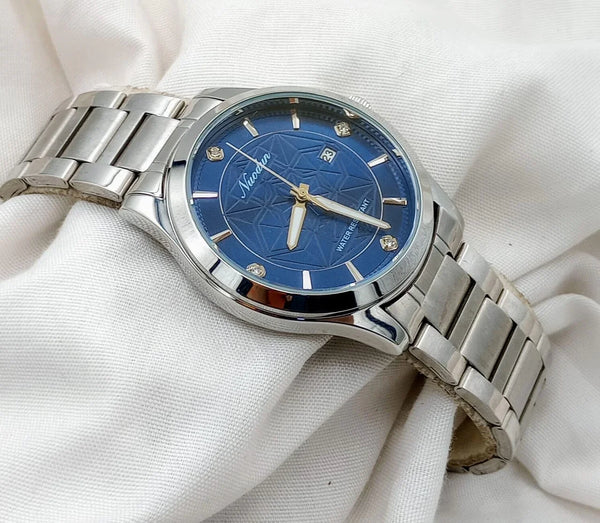 Silver stainless steel wristwatch with blue dial and date display on white fabric background